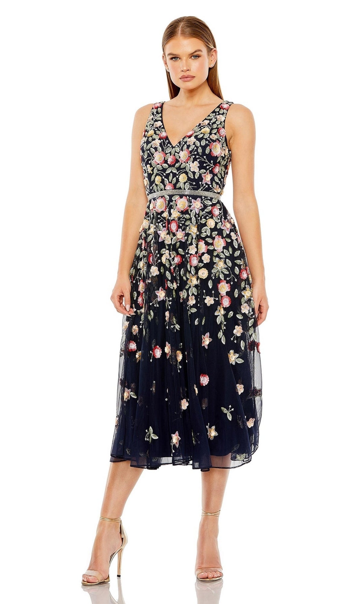 A woman in the Mac Duggal 5527 Floral-Embroidered Party Dress, a sleeveless, navy semi-formal V-neck with floral details, paired with nude high heels.